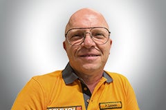 Porträt eines lächelnden Mannes mit Brille und orangefarbenem Hemd