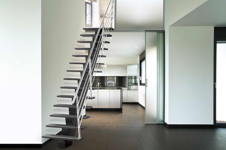 Treppe mit Stahlgeländer in einem hellen Raum mit Küche