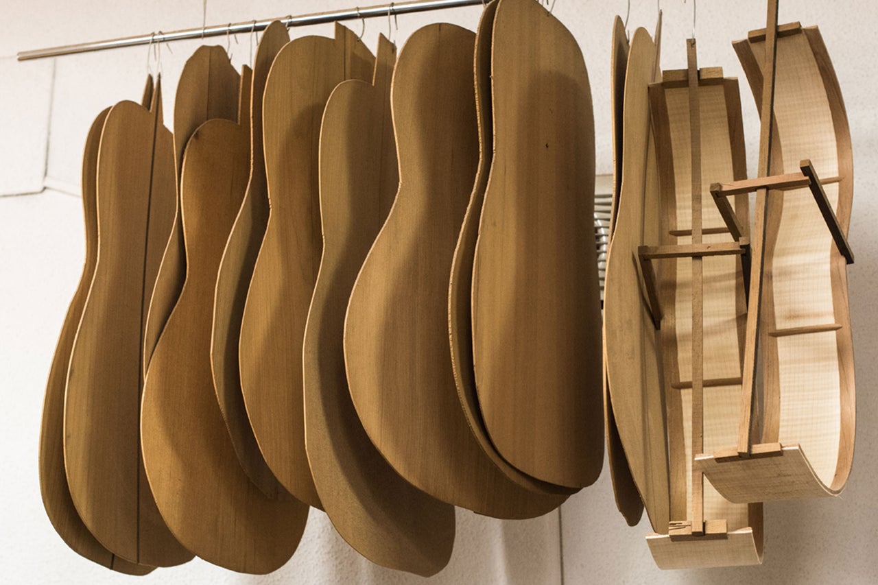 Mehrere Gitarrenrohlinge aus Holz hängen an einer Stange.