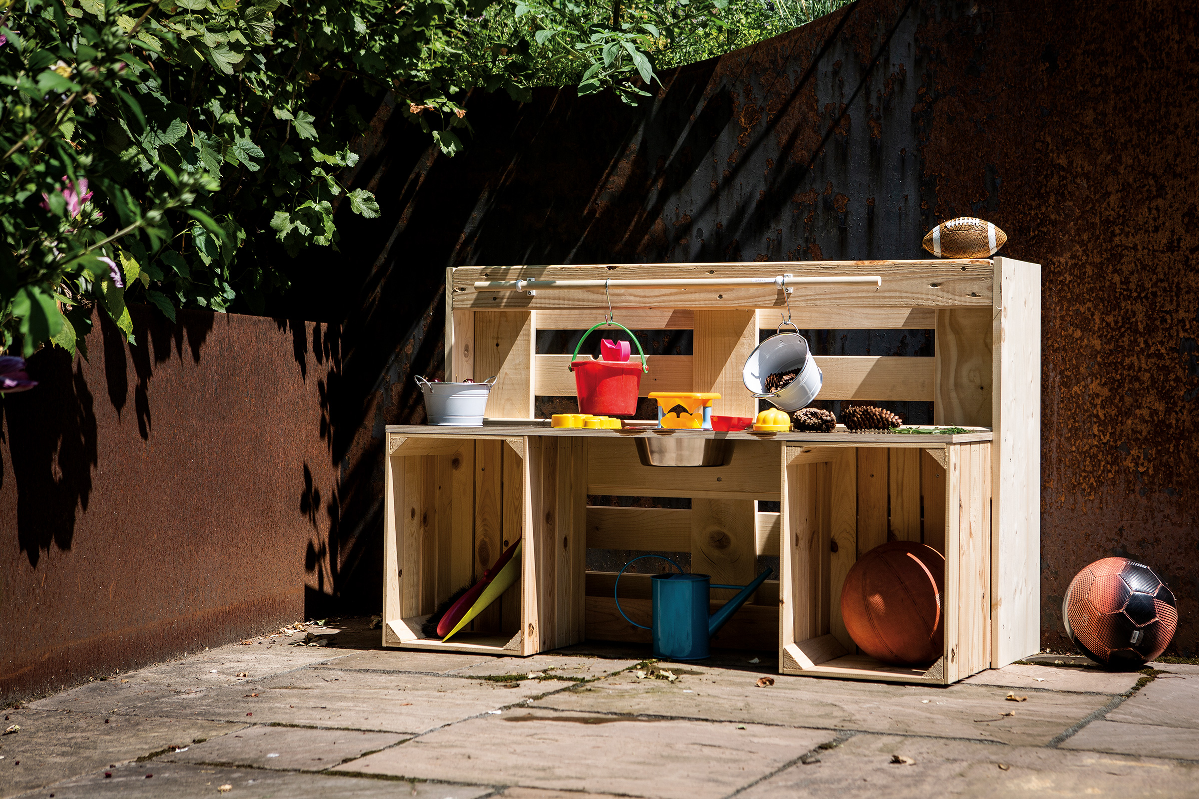 Spielküche aus Holz mit Spielzeug im Garten