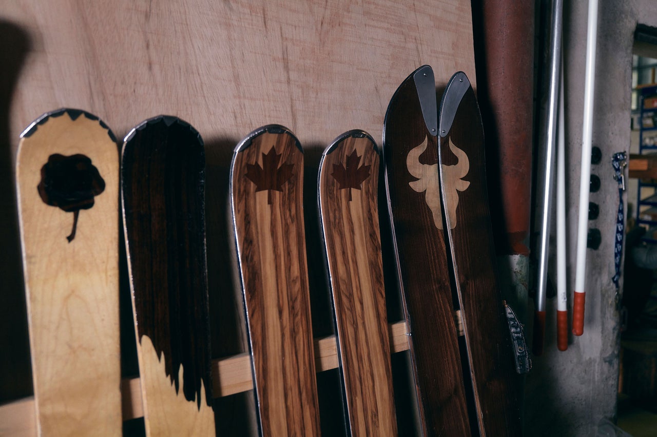 Mehrere Holzskier mit verschiedenen Mustern lehnen an einer Wand.