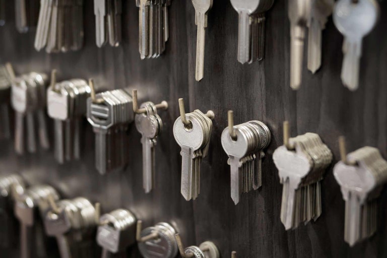 Viele Schlüssel hängen an einer dunklen Holztafel.