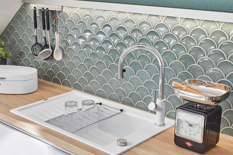 Küchenszene mit Spüle, Armatur, Geschirrtuchhalter, Küchenhelfern und Fliesen