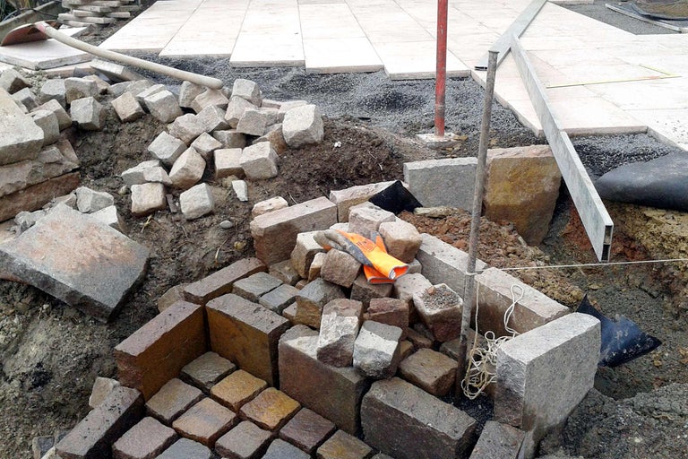 Baustelle mit Pflastersteinen und Werkzeugen für die Gartengestaltung