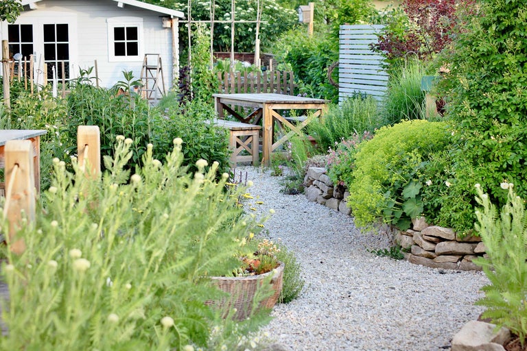 Gartenanlage mit Gartenhaus, Holztisch und Kiesweg