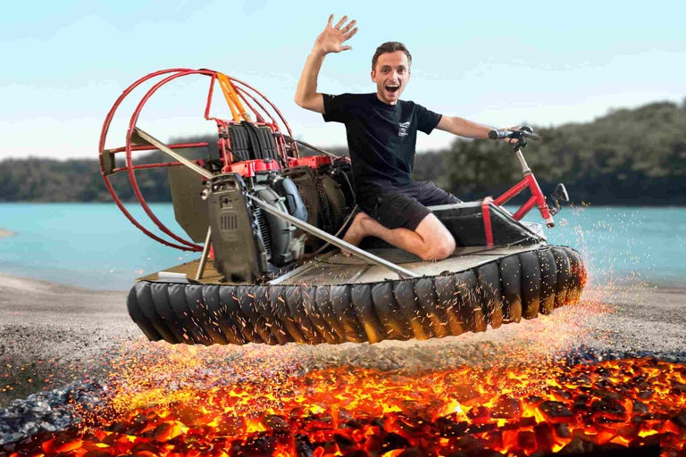 Ein Mann fährt ein Hovercraft über glühende Kohlen.