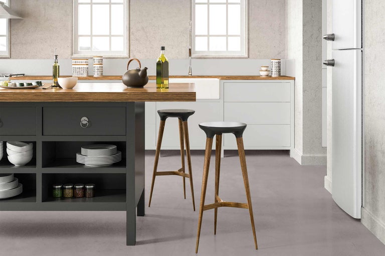 Küchenszene mit Kücheninsel, Geschirr, Gewürzen, Barhockern und Kühlschrank.