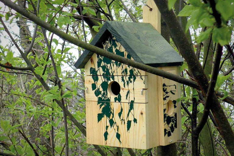 Holz-Vogelhaus mit Rankenmuster an einem Baum