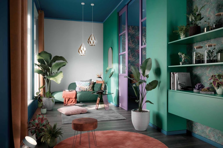 Ein Wohnzimmer mit einem Sofa, einem Tisch, einem Hocker, Teppichen, Pflanzen und dekorativen Elementen.