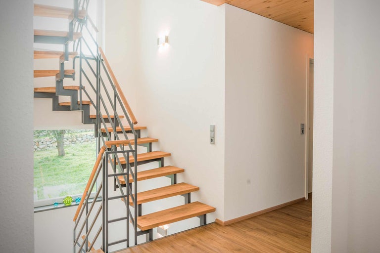Treppenhaus mit Holzstufen und Metallgeländer in einem hellen Wohnbereich