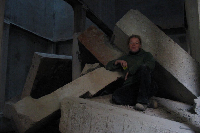 Frau sitzt auf Betonblöcken in einem Rohbau