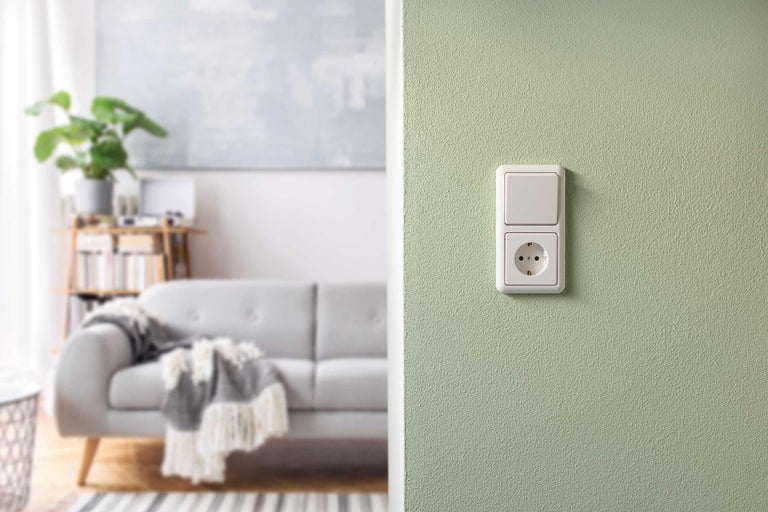 Schalter und Steckdose an einer Wand im Wohnzimmer