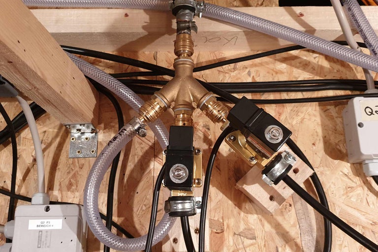 Verteiler mit Rohren und Kabeln an einer Holzwand