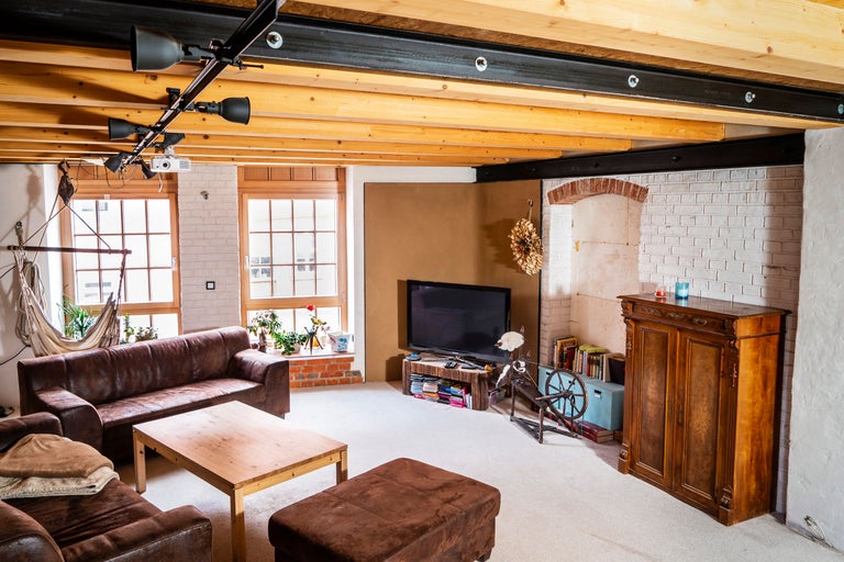 Wohnzimmer mit Ledersofa, Holztisch und Fernseher