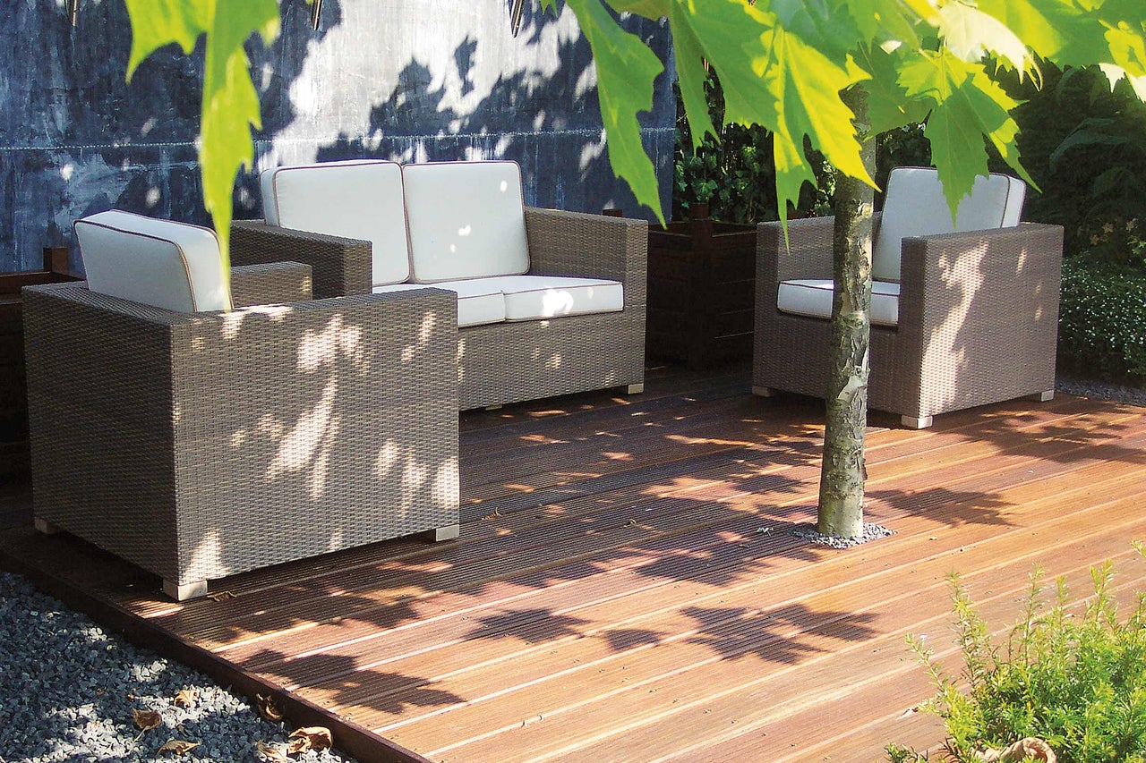 Gartensitzgruppe aus Polyrattan mit hellen Polstern auf Holzterrasse