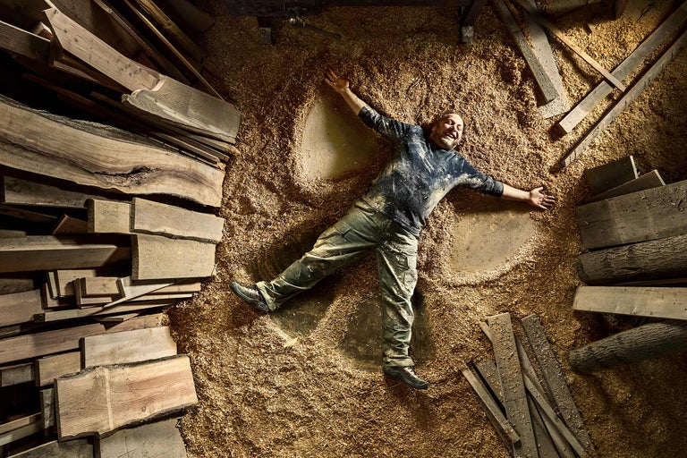 Mann liegt in Holzspänen zwischen Holzbrettern