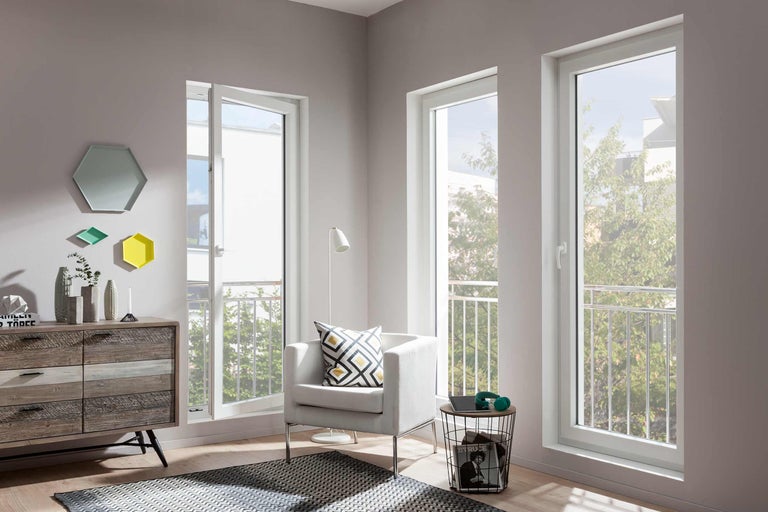 Heller Wohnraum mit weißen Kunststofffenstern, Sessel und Kommode