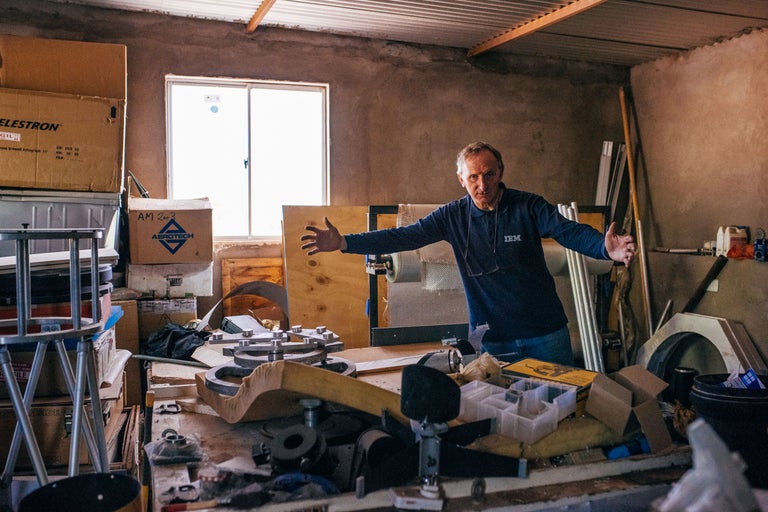 Mann steht in einem Raum voller Werkzeuge und Kisten, darunter eine Celestron-Box und eine Aerotech-Box.