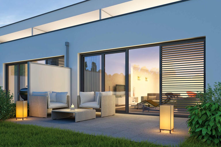 Terrasse mit Gartenmöbeln und Beleuchtung vor einem modernen Haus