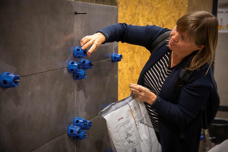 Frau arbeitet mit Fliesen, Nivelliersystem und einer Verpackung