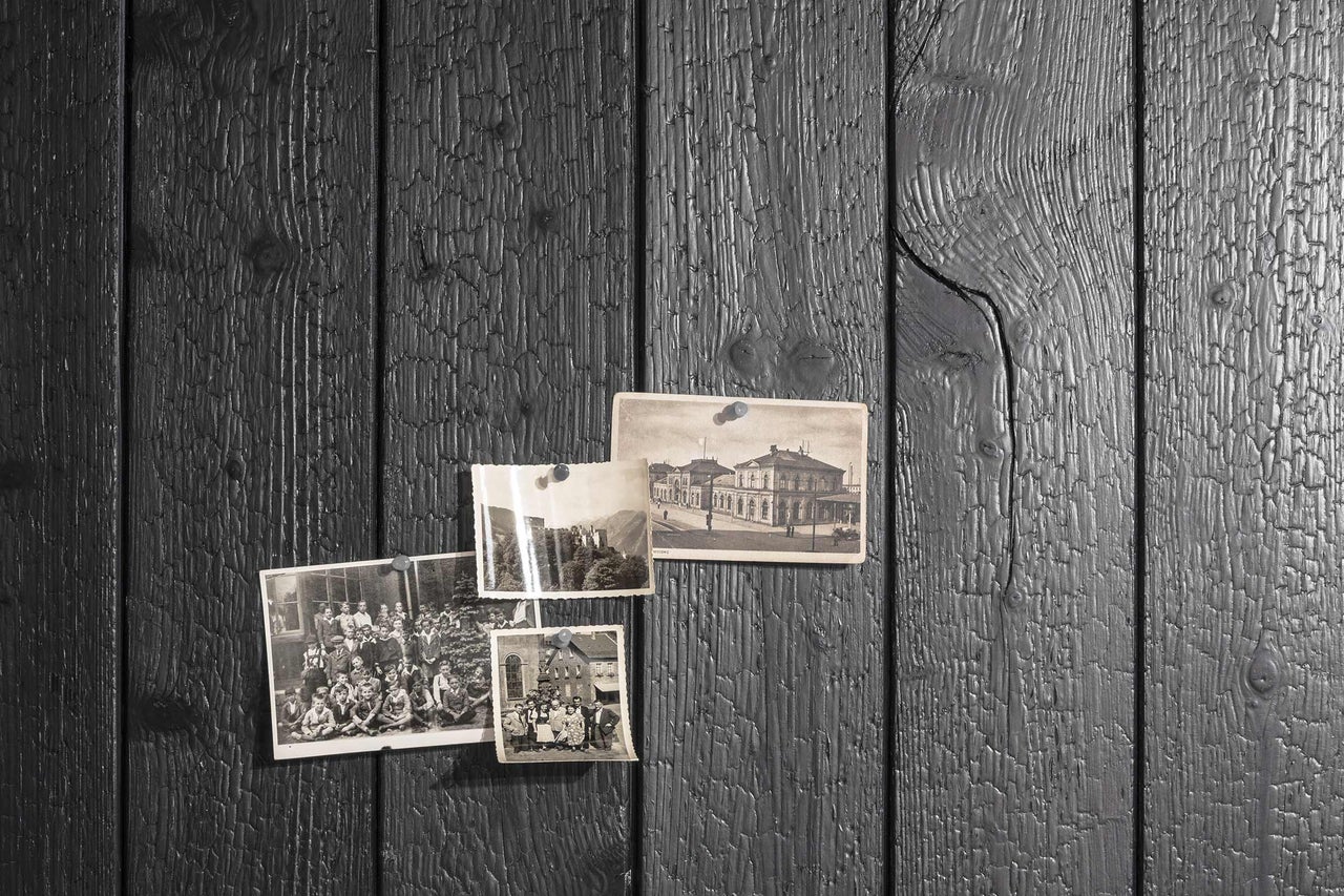 Dunkle Holzvertäfelung mit historischen Fotos, befestigt mit Reißzwecken.