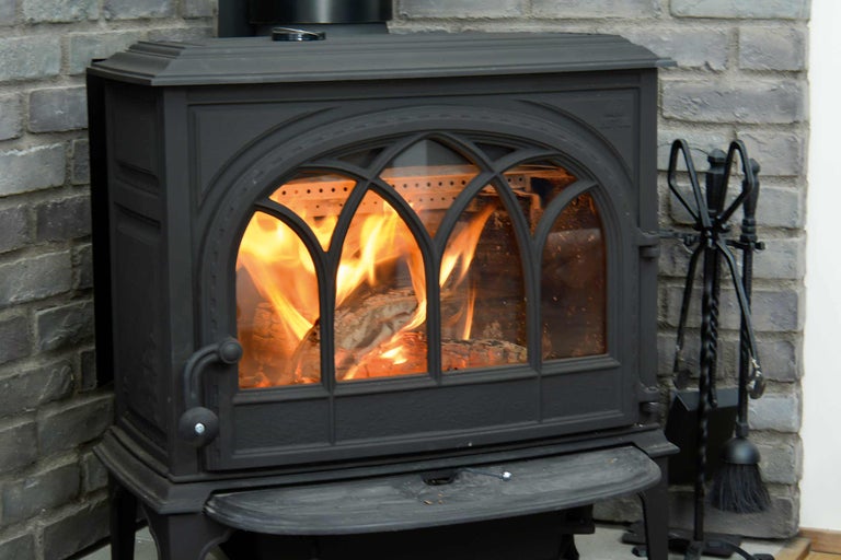 Brennender Kaminofen mit Kamingarnitur vor einer Backsteinwand