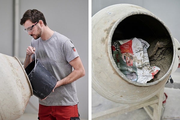 Mann mit Schutzbrille schüttet Inhalt aus Eimer in Betonmischer