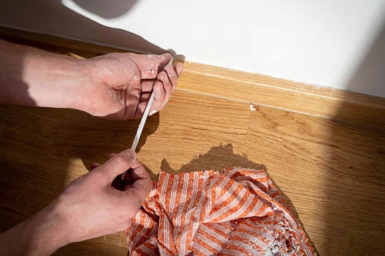 Reinigen einer Sockelleiste mit Spachtel und Tuch