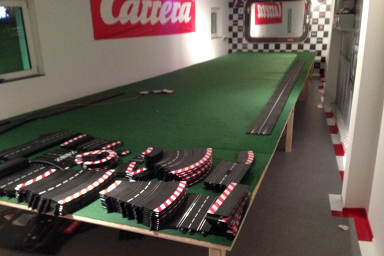Rennbahn mit Schienenteilen und Carrera Logo an der Wand