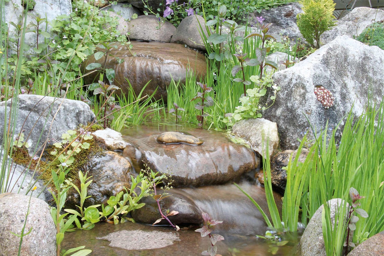 Bachlauf im Garten mit Steinen und Bepflanzung