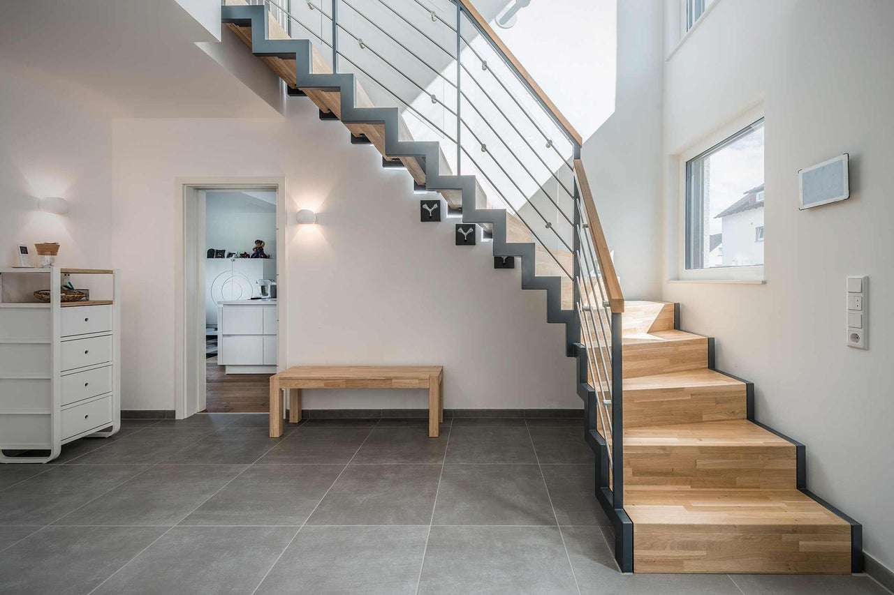 Heller Raum mit Holztreppe, Sitzbank und Kommode