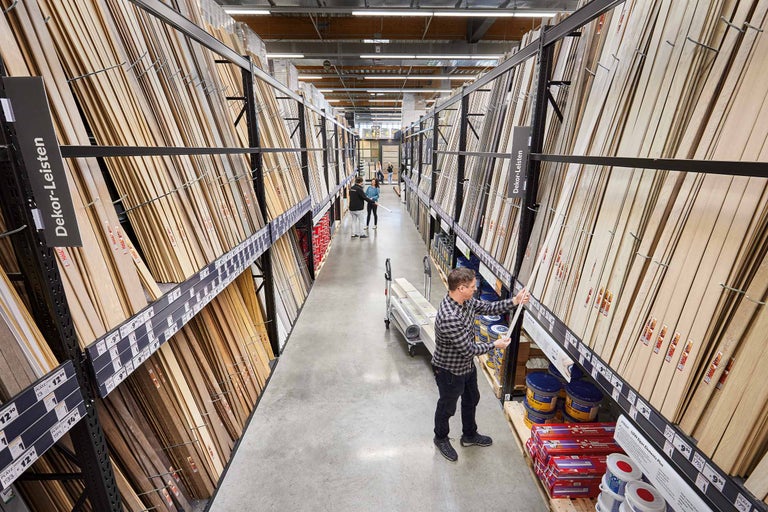 Gang in einem Hornbach Markt mit Dekorleisten in Regalen und einem Kunden, der diese begutachtet