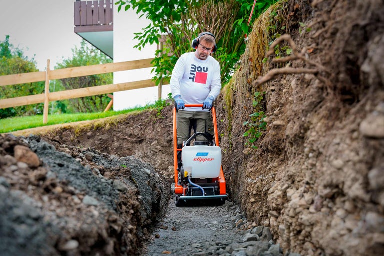 Ein Mann verdichtet mit einer Rüttelplatte den Untergrund für ein Bauprojekt.