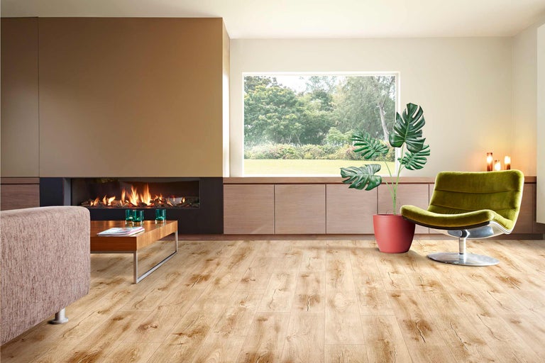 Heller Wohnraum mit Kamin, Holzfußboden, Sessel und Zimmerpflanze.