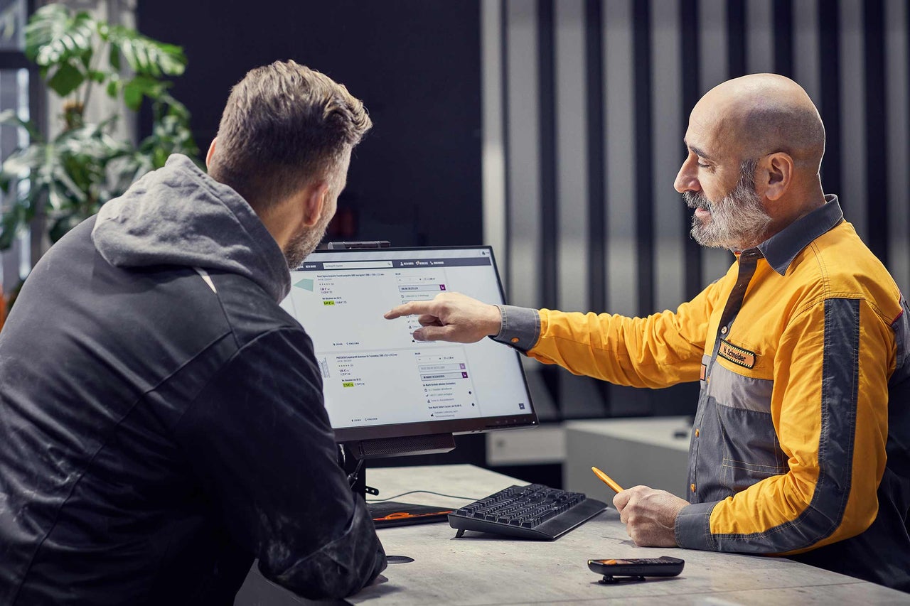 Ein Hornbach Mitarbeiter berät einen Kunden am Computer zu Produkten.