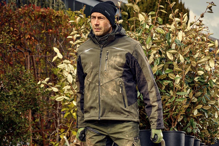 Mann in Arbeitskleidung mit Pflanzen im Freien.