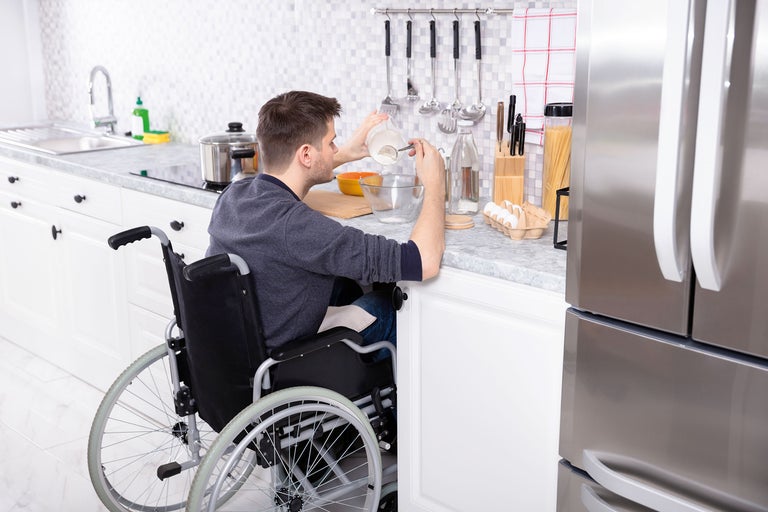 Mann im Rollstuhl bereitet Speisen in einer zugänglichen Küche zu