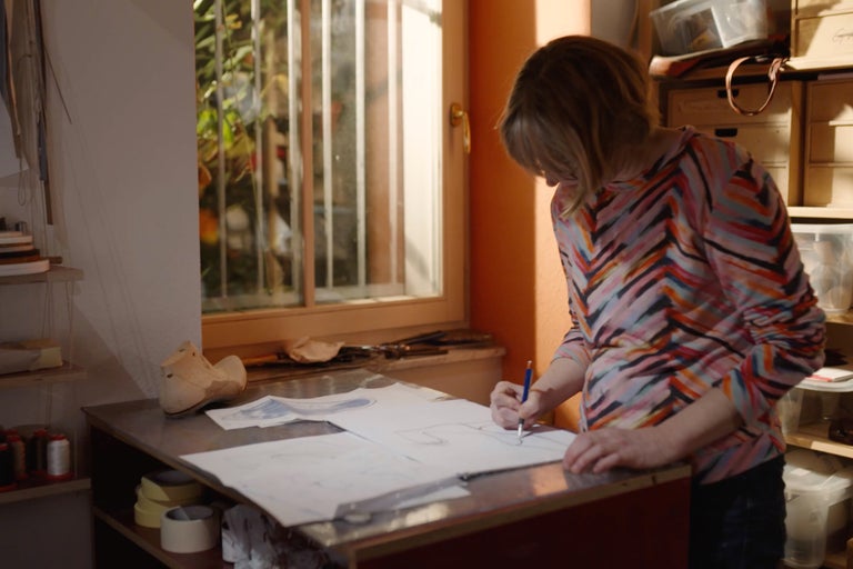Eine Frau zeichnet einen Entwurf auf Papier in einer Werkstatt.