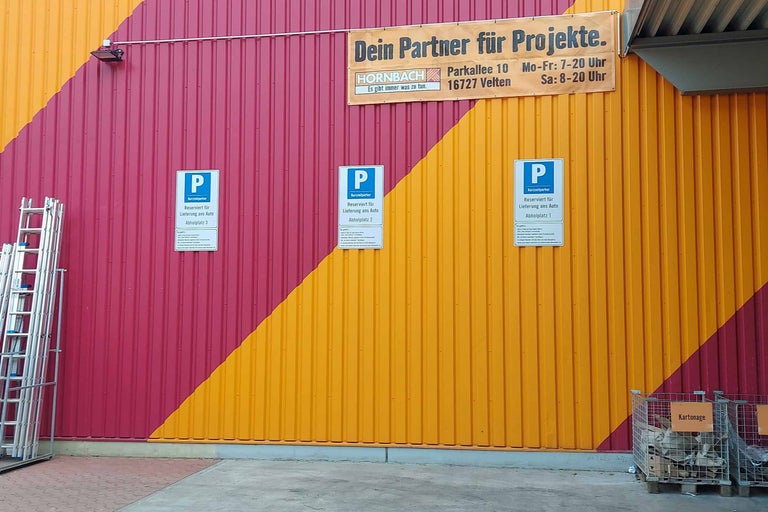 Außenansicht eines Hornbach Baumarktes mit Hinweisschildern für reservierte Kurzzeitparkplätze zur Warenabholung