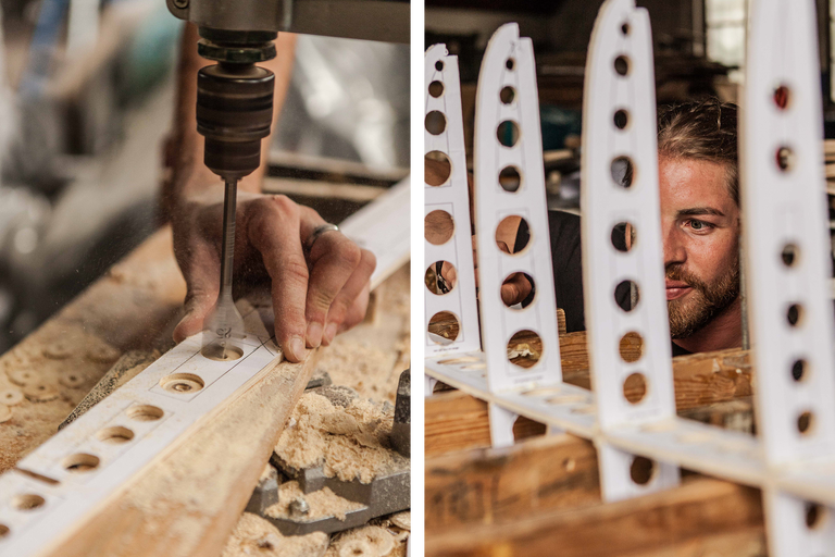 Mann bohrt Löcher in ein Holzbrett mit einem Holzbohrer. Im Hintergrund sind weitere Holzbretter mit Löchern zu sehen.