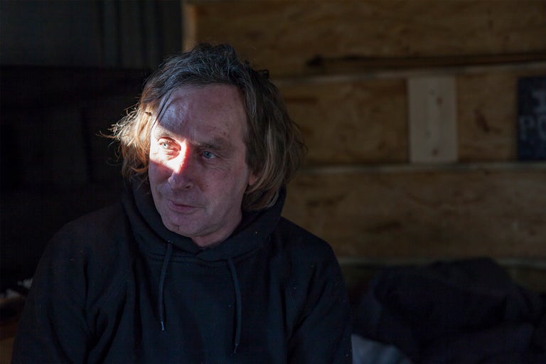 Porträt eines Mannes mit Kapuzenpullover vor Holzwand