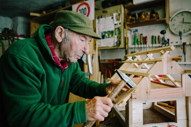 Ein Mann hämmert in einer Werkstatt ein Holzhaus zusammen.