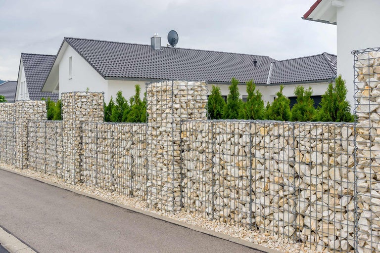 Gabionenzaun mit Steinen vor einem Wohnhaus