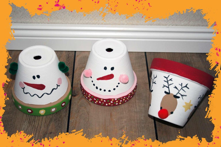 Drei bemalte Blumentöpfe mit Wintermotiven auf einem Holzboden.