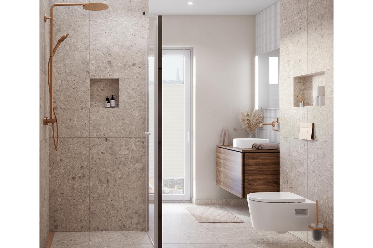 Modernes Badezimmer mit großformatigen Fliesen in Natursteinoptik, ebenerdiger Dusche mit kupferfarbenen Armaturen, Waschtisch und Wand-WC.
