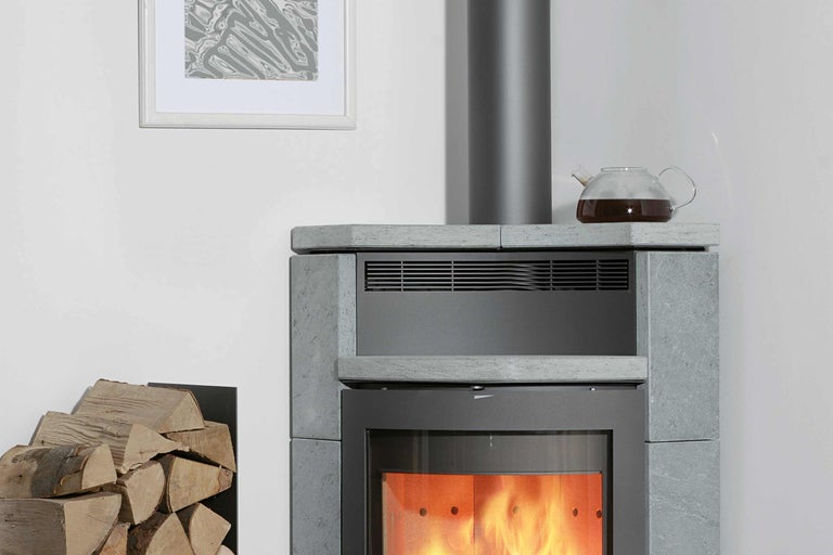 Kaminofen mit Holzscheitlagerung und Teekanne