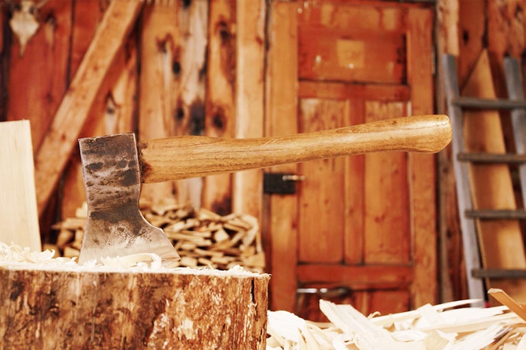 Axt steckt in einem Holzscheit vor einer Holzwand