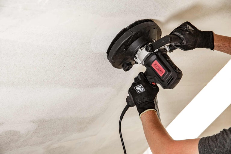 Ein Handwerker verwendet einen Deckenschleifer von JC Schwarz, um eine Decke zu bearbeiten.