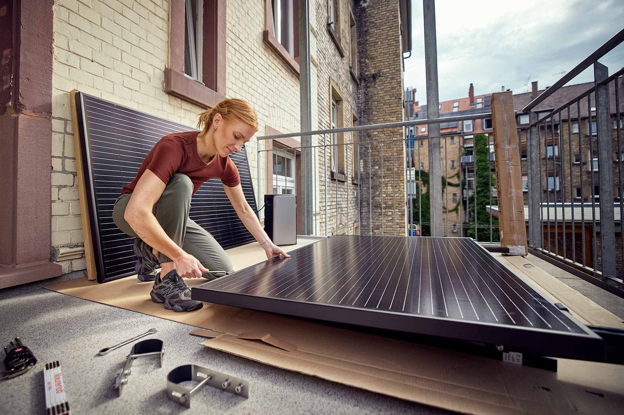 Frau montiert eine Balkonsolaranlage.