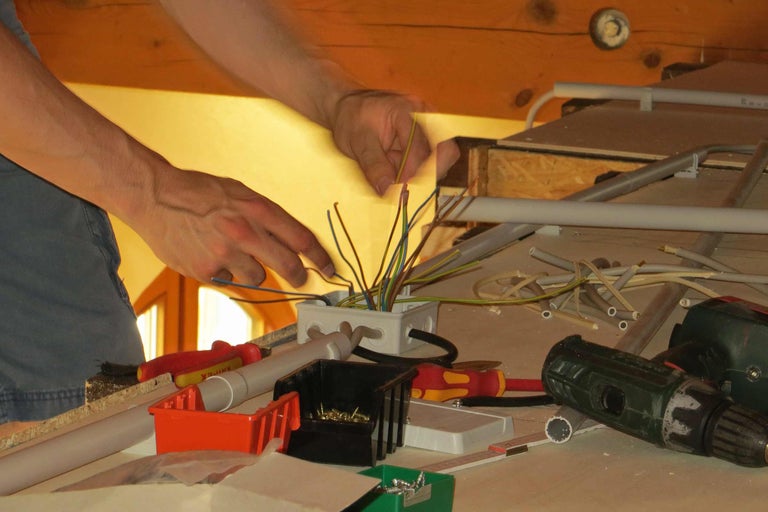 Elektriker bei der Arbeit an einer Verteilerdose mit Kabeln.